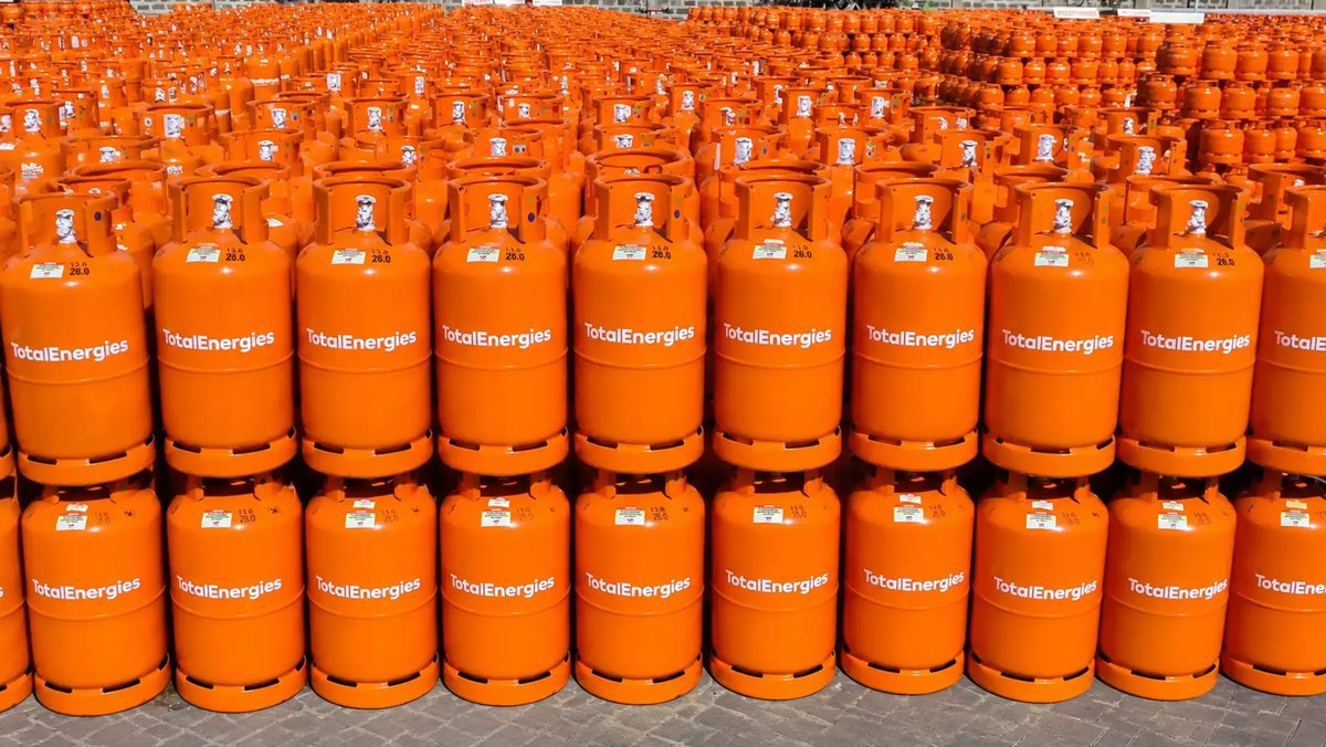 TotalEnergies photo: rows of orange TotalEnergies 13 kg LPG cylinders standing upright, stacked two high, outdoors on paving.